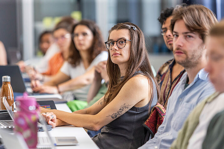 Participants seated at a table, listening to a presentation.