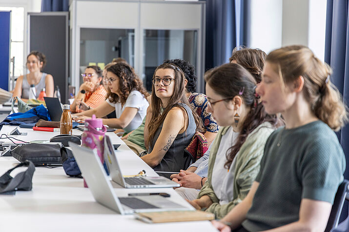 Participants seated at a table, listening to a presentation